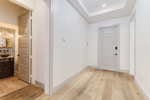 hallway featuring a raised ceiling and light wood-type flooring