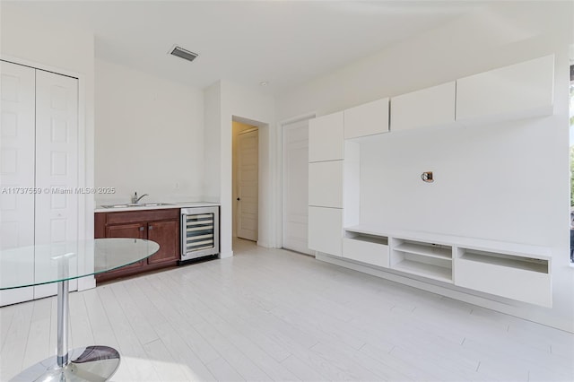 interior space with wine cooler, light hardwood / wood-style flooring, and wet bar