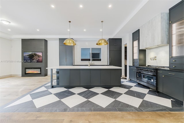 kitchen with pendant lighting, gray cabinets, range with two ovens, and a center island with sink