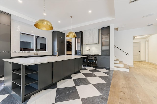 kitchen with gray cabinets, pendant lighting, sink, a large island, and light hardwood / wood-style floors