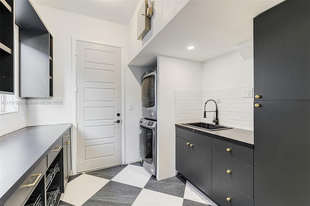 kitchen featuring stacked washer and dryer, backsplash, and sink