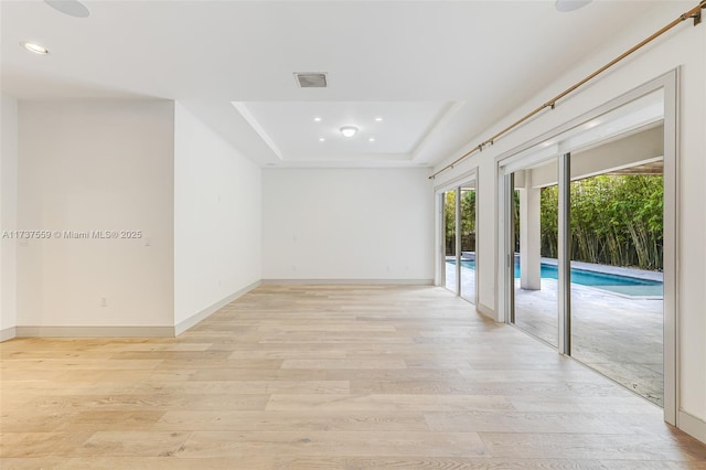 unfurnished room featuring a tray ceiling and light hardwood / wood-style floors