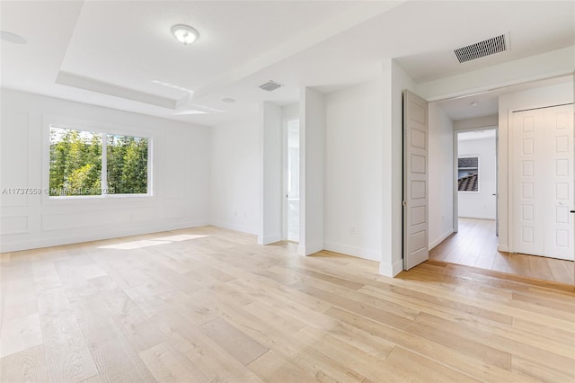 spare room featuring light hardwood / wood-style floors and a tray ceiling