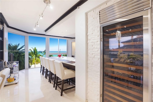 dining area with a water view, track lighting, and wine cooler