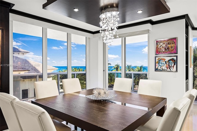 dining space featuring a water view, crown molding, and an inviting chandelier