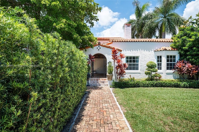 2424 Prairie Ave, Miami Beach, FL 33140 - mediterranean / spanish-style house featuring a chimney, a tiled roof, stucco siding, and a front lawn