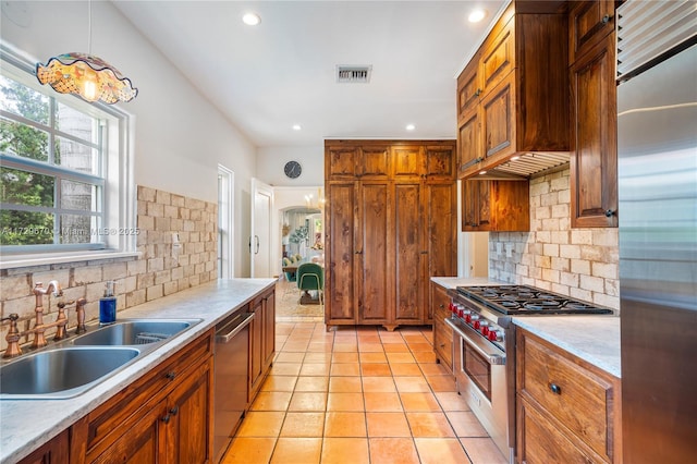 kitchen with premium range hood, pendant lighting, tasteful backsplash, sink, and stainless steel appliances