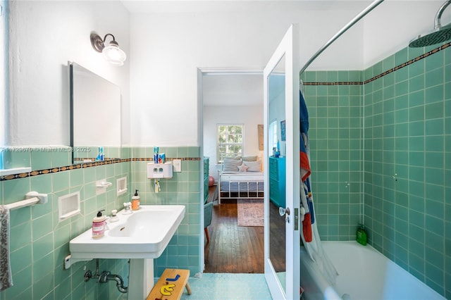 bathroom with hardwood / wood-style floors, shower / bath combo, and tile walls