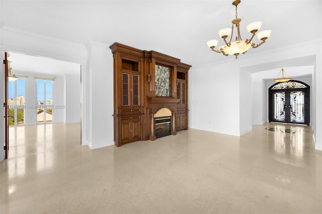 unfurnished living room featuring a notable chandelier, crown molding, and french doors