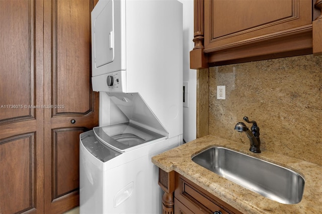 washroom featuring sink, cabinets, and stacked washing maching and dryer