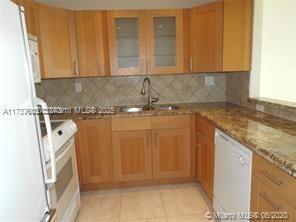 kitchen featuring sink, light stone counters, backsplash, and white appliances