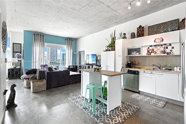 kitchen featuring sink, dishwasher, white cabinetry, backsplash, and a center island