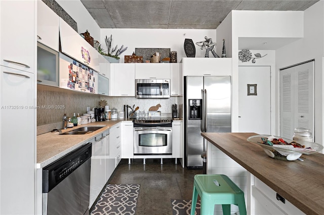 kitchen with sink, appliances with stainless steel finishes, white cabinetry, backsplash, and butcher block counters