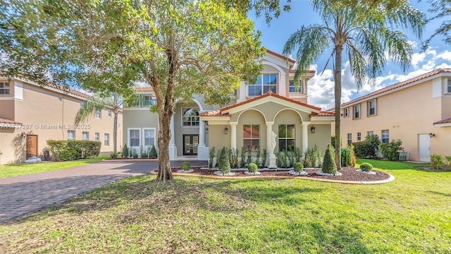 mediterranean / spanish-style home with a tile roof, a front lawn, decorative driveway, and stucco siding