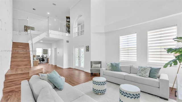 living area featuring french doors, wood finished floors, a high ceiling, and baseboards