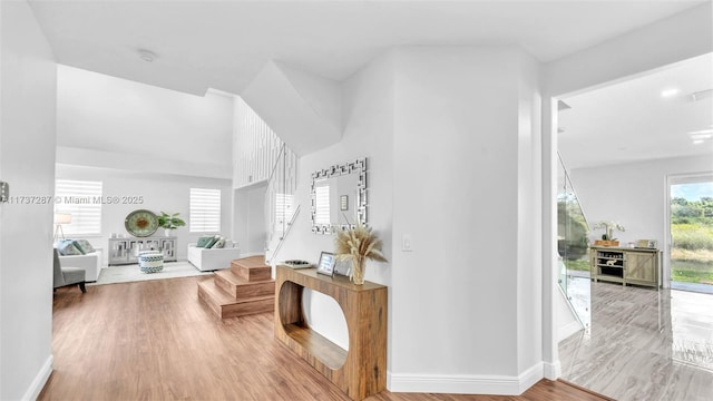 hall with wood finished floors, baseboards, and stairs