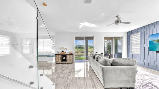 living area featuring ceiling fan and a textured ceiling