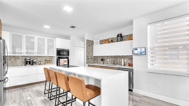 kitchen with visible vents, appliances with stainless steel finishes, a breakfast bar, a center island, and white cabinetry