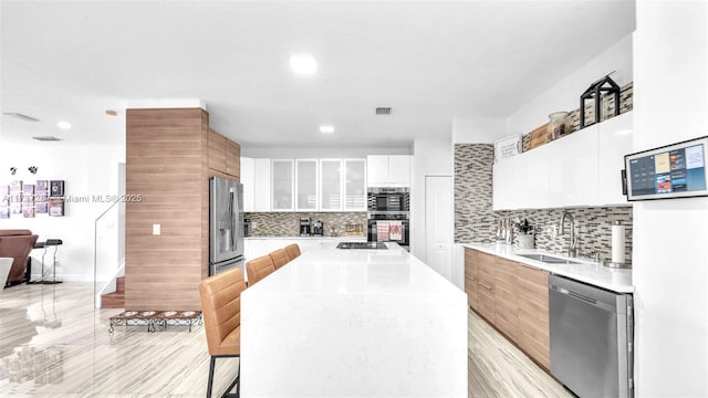 kitchen with light countertops, visible vents, appliances with stainless steel finishes, a sink, and modern cabinets