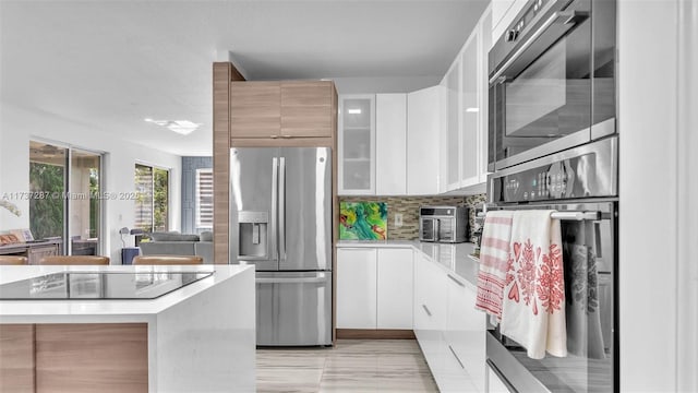 kitchen with tasteful backsplash, light countertops, appliances with stainless steel finishes, white cabinets, and modern cabinets