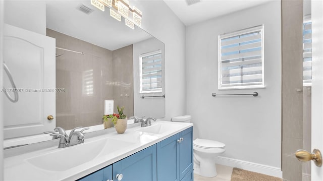 bathroom with double vanity, a sink, toilet, and baseboards