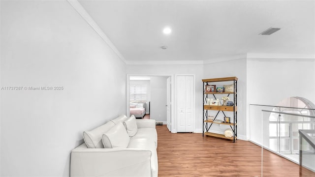 living area featuring baseboards, crown molding, visible vents, and wood finished floors