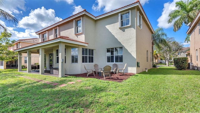 back of property featuring a yard, a tiled roof, a patio area, and stucco siding