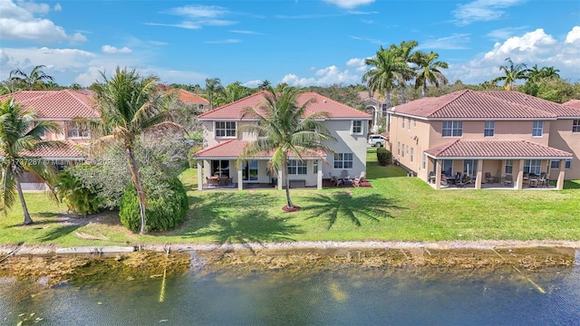 back of property with a lawn, a tile roof, a water view, a patio area, and stucco siding