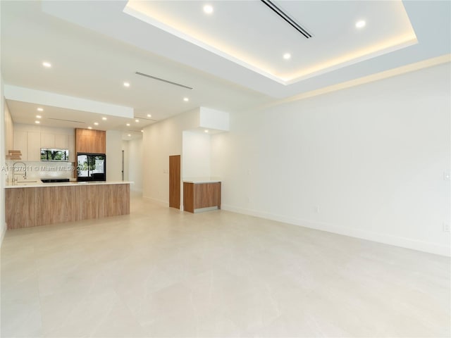 unfurnished living room with sink and a raised ceiling