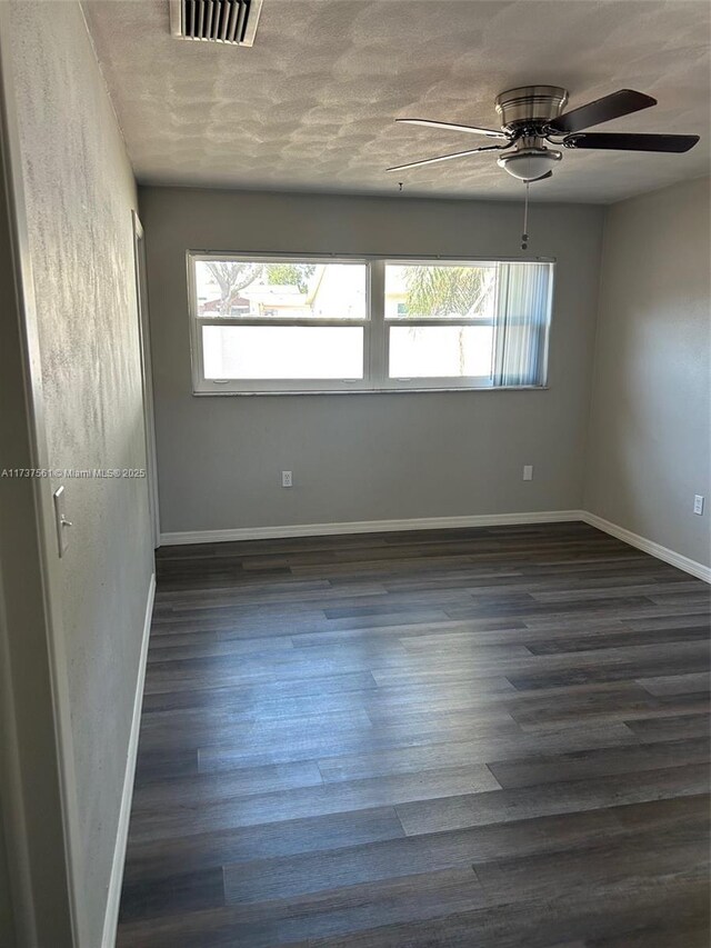 7403 Foxbloom Dr, New Port Richey, FL 34668 - empty room with plenty of natural light, dark wood-style floors, baseboards, a ceiling fan, and a textured ceiling