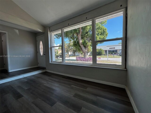 7403 Foxbloom Dr, New Port Richey, FL 34668 - empty room featuring vaulted ceiling, dark wood-type flooring, and baseboards