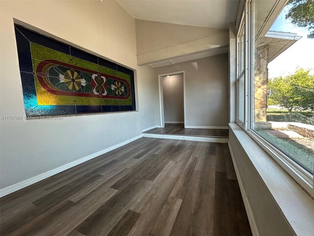 7403 Foxbloom Dr, New Port Richey, FL 34668 - empty room featuring vaulted ceiling, healthy amount of natural light, dark wood-style floors, and baseboards