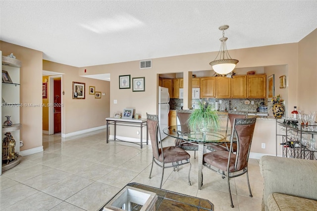 dining space featuring light tile patterned floors and a textured ceiling