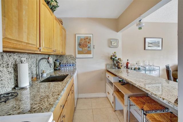 kitchen featuring sink, light tile patterned floors, backsplash, and light stone counters