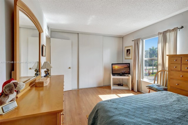 bedroom featuring a closet, a textured ceiling, and light hardwood / wood-style flooring