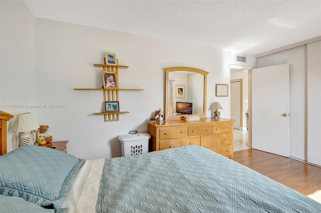 bedroom with wood-type flooring and a textured ceiling