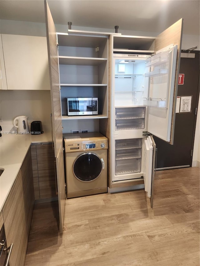 laundry room with washer / dryer and light hardwood / wood-style flooring