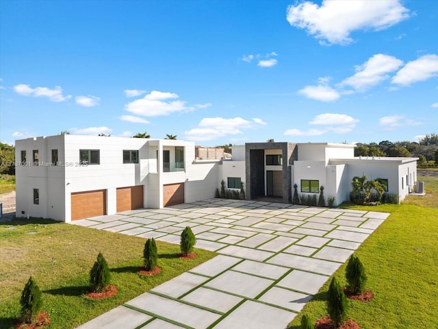 rear view of house with a garage, cooling unit, and a lawn