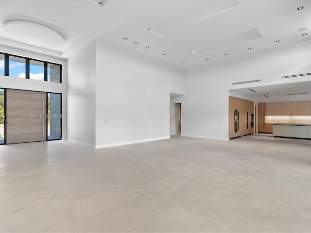 unfurnished living room featuring a towering ceiling