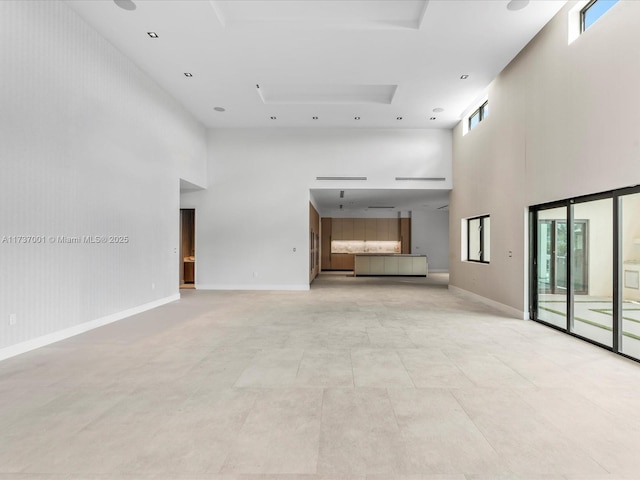 unfurnished living room featuring a towering ceiling