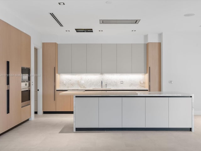 kitchen featuring white cabinetry, black microwave, oven, and backsplash