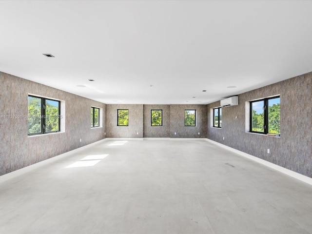 unfurnished room featuring a wall mounted air conditioner and a wealth of natural light