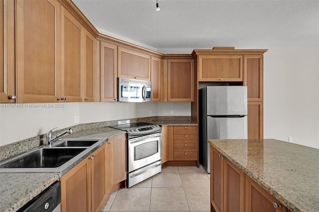 kitchen with light tile patterned floors, stainless steel appliances, a sink, a textured ceiling, and light stone countertops