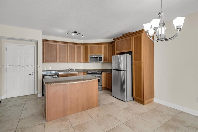 kitchen featuring light tile patterned floors, stainless steel appliances, dark countertops, a kitchen island, and a sink