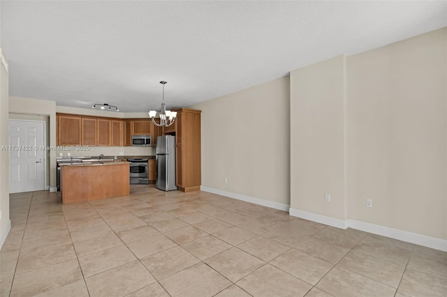 kitchen with open floor plan, appliances with stainless steel finishes, a center island, brown cabinetry, and decorative light fixtures