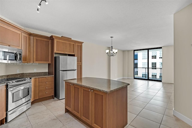 kitchen featuring brown cabinetry, light tile patterned floors, stainless steel appliances, and a center island