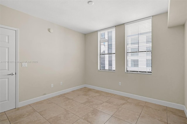 unfurnished room with light tile patterned floors and baseboards