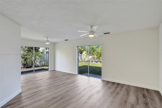 empty room featuring ceiling fan, wood-type flooring, a textured ceiling, and plenty of natural light