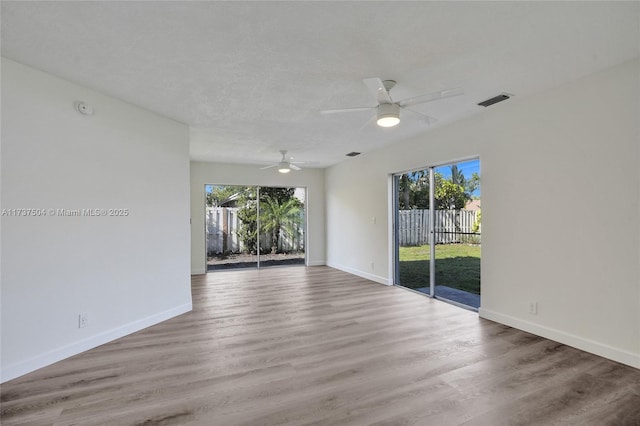 spare room featuring ceiling fan, hardwood / wood-style floors, and a wealth of natural light