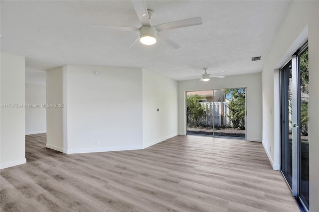 empty room featuring ceiling fan, light hardwood / wood-style flooring, and a textured ceiling